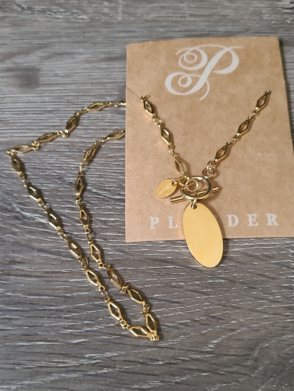Plunder gold-tone oval pendant necklace with decorative link chain.